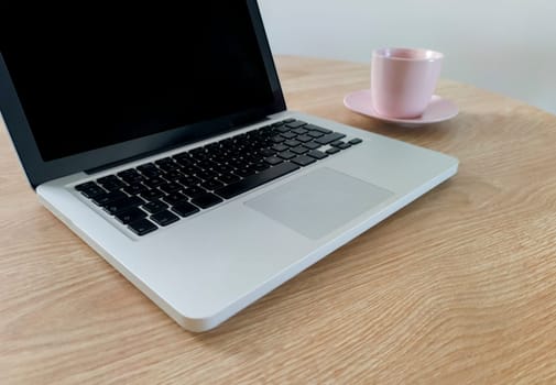 Living room table with laptop and pink blush mug. Domestic workspace concept