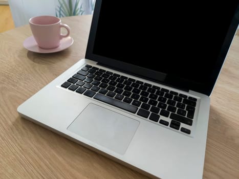 Living room table with laptop and pink blush mug. Domestic workspace concept