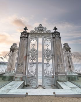 Pair of elaborately decorated white painted metal gates leading to the opulent Dolmabahce Palace in Istanbul, Turkey, and offering stunning views of the Bosphorus Strait