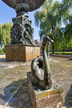 Close-up of the swan statue at the Molin's Fountain in Kungstradgarden, Stockholm, Sweden. The fountain is surrounded by lush green trees, creating a serene and peaceful scene