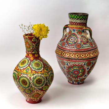 Beautiful Egyptian handcrafted artistic ornate pottery jars decorated with geometrical colorful patterns, with yellow flower on white background