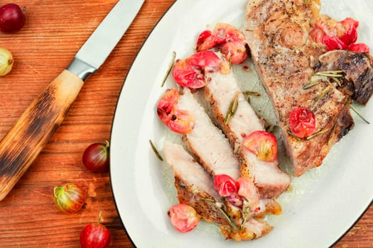 Delicious grilled beef steak with gooseberry on rustic wooden table.