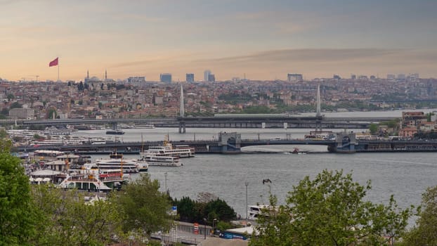 Panoramic skyline of European side of Istanbul with ferry boats sailing in Bosphorus strait, overlooking Halic Metro Bridge with clear sky in a spring day before sunset, Istanbul, Turkey