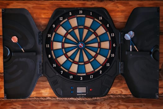 Bright multicolored dartboard hangs on wall. Close-up. Games and entertainment. Excitement and sport. Decorative elements. Design. Darts. Game board. Training and sports.