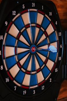 Close-up. Bright multicolored dartboard hangs on wall. Games and entertainment. Excitement and sport. Decorative elements.Design. Darts. Game board. Training and sports.