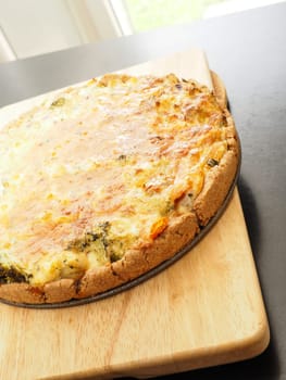 Tasty organic vegetable quiche on a cutting board in a kitchen, healthy eating or diet concept, vegetarian food