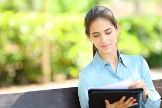 Businesswoman checking documents sitting on a bench in a park
