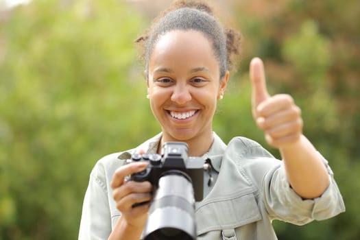Front view portrait of a happy black photographer with thumbs up