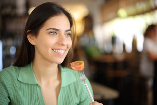 Happy customer eating tomato in a restaurant interior