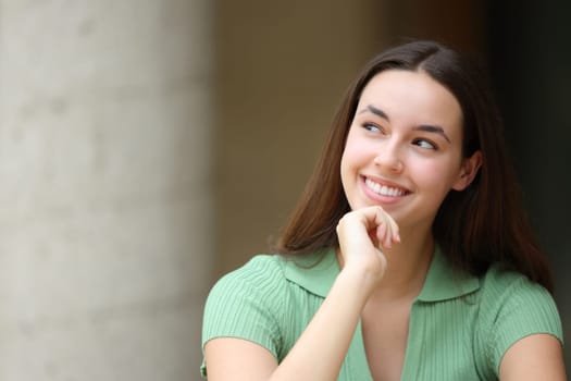 Happy woman in the street thinking looking at side