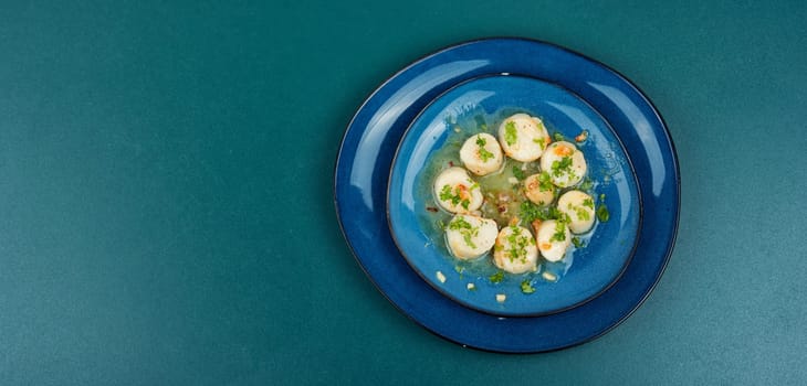 Roasted scallops with green, grilled sea scallops in creamy sauce. Wooden background.