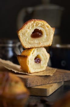Pasticciotto leccese pastry filled with egg custard cream and sour cherry jam. Whole and half pasticiotties served on a wooden board for typical apulian breakfast with coffee, close up