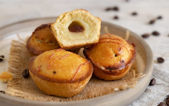 Pasticciotto leccese pastry filled with egg custard cream and sour cherry jam. Whole and half pasticiotties on a plate served for typical apulian breakfast, close up. Table decorated with coffee beans