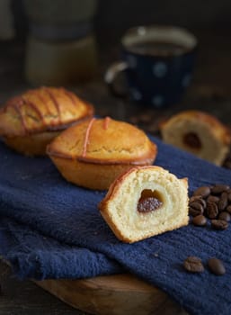 Pasticciotto leccese pastry filled with egg custard cream and sour cherry jam. Whole and half pasticiotties served for typical apulian breakfast with coffee, close up. Table decorated with coffee beans