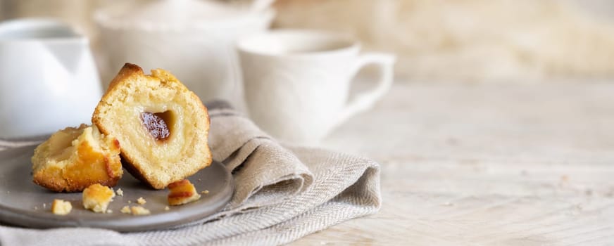 Pasticciotto leccese pastry filled with egg custard cream and sour cherry jam. Pieces of pasticiotto on a plate on a white rustic wooden table, typical apulian breakfast with coffee, close up, copy space