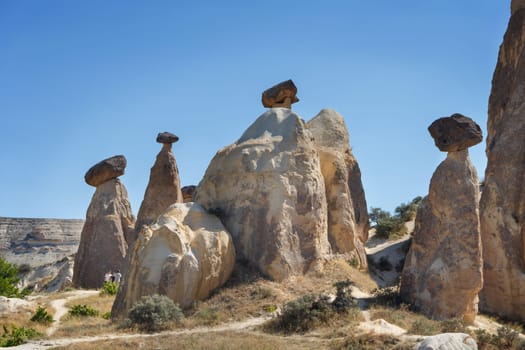 Unique geological rock formations Fairy Chimneys in Cappadocia against blue sky in summer. Popular touristic area in Goreme, Nevsehir, Turkey