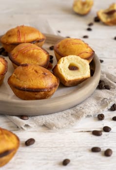 Pasticciotto leccese pastry filled with egg custard cream and sour cherry jam. Whole and half pasticiotties on a plate served for typical apulian breakfast, close up. Table decorated with coffee beans