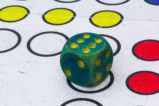 Green and red dice on the floor in a game of board games. A die indicates the six.