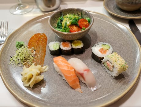A plate with salad and sushi rolls, fresh raw fish.