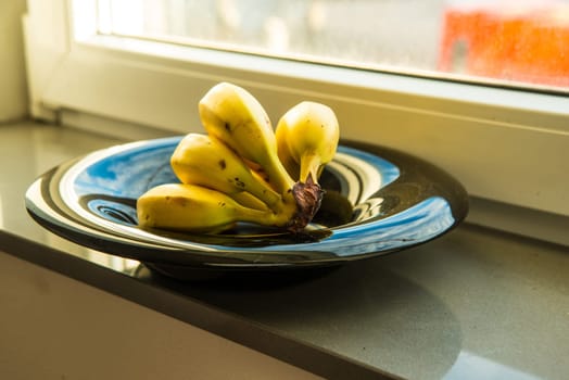 ripe bananas in a black fruit bowl on a window sills