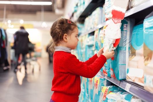 Little girl selects diapers in supermarket.