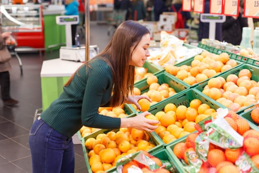 Young girl buys oranges in a grocery store.