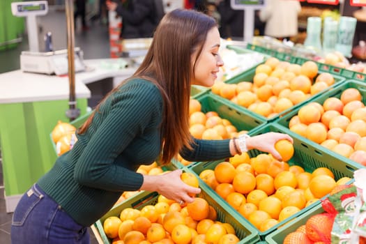 A young woman in a store chooses oranges