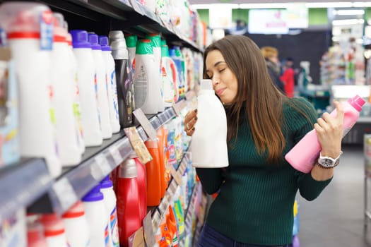 Young woman compares abstergents gel in shop