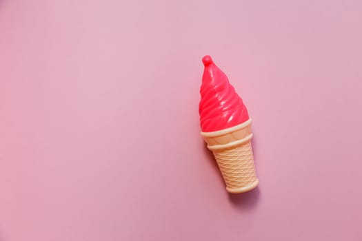 Plastic strawberry fake ice cream on a pink background.