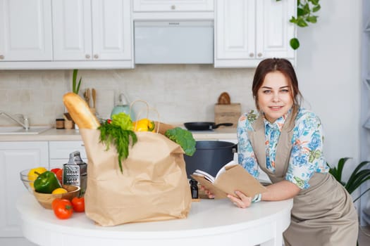 Young caucasian woman with recipe book at the kitchen