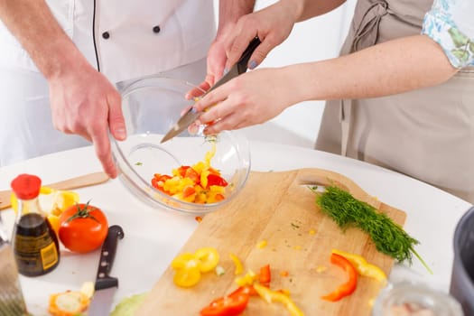 A woman is preparing a salad led by a professional chef