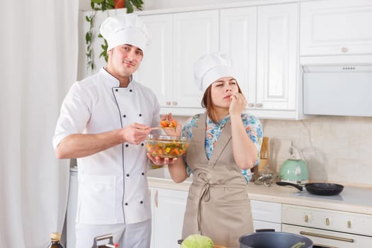 Funny senior chef with big white hat and pot of beans
