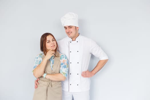 Confident chef wearing uniform shoulder to shoulder with pretty young woman assistant