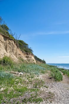 Island Poel on the steep coast to the Baltic Sea. Break-off edge on the slope, in front of it beach with grass. Coastal landscape in summer. Vacation resort