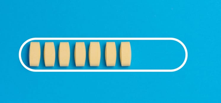Yellow oval tablets on a blue background, top view