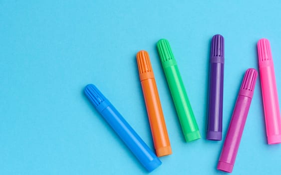 Multicolored felt-tip pens on a blue background, top view