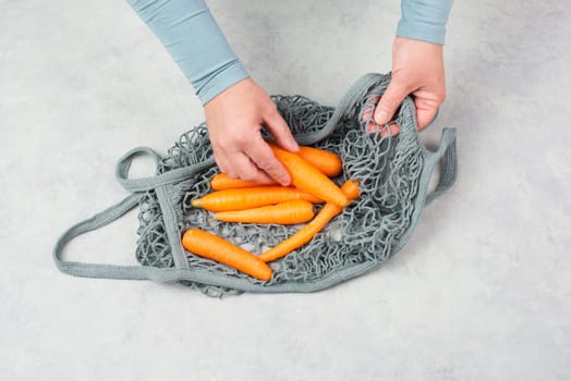 Unpack fresh carrots from a reusable grocery mesh bag, vegetables from the market, healthy food and zero waste