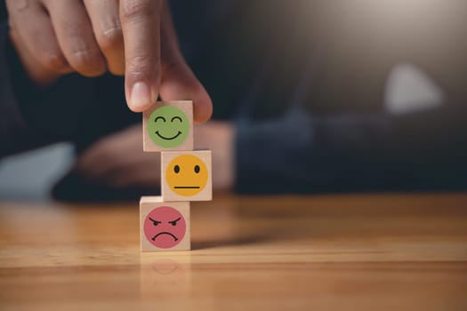The businessman selects a smiley face on a wooden block to rate the quality of excellent business services. Satisfaction survey and feedback concept. 5-star satisfaction is guaranteed.