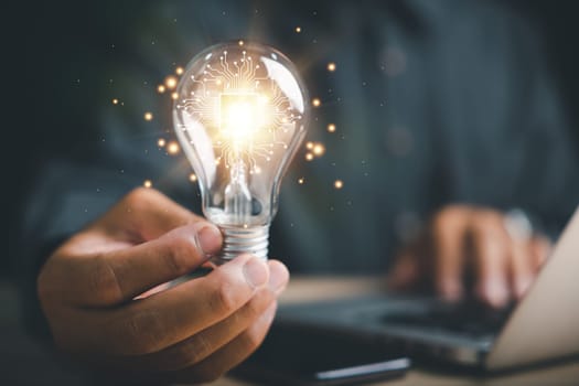 Creative businessman holds a light bulb, representing an innovative idea. Highlights the concept of brainstorming, solution, and successful profit in global business.