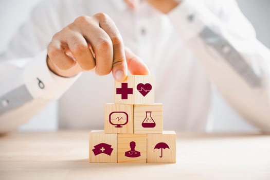 Wooden block held by hand features healthcare and medical icons, portraying safety, health, and family well-being. Reflecting pharmacy, heart care, and happiness. health care concept