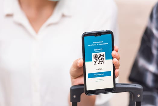 Young woman ready to travel showing digital vaccine health passport certificate app in smartphone screen during coronavirus pandemic, Mobile app of virus COVID-19 vaccination