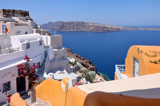 Oia, Santorini, Greece - July 3, 2021: Whitewashed buildings and the ruins of Castle of Agios Nikolaos on the edge of the caldera cliff, Oia village, Santorini, Greece