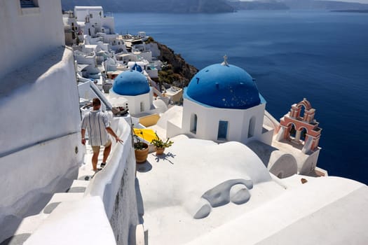 Oia, Santorini, Greece - July 3, 2021: Whitewashed buildings on the edge of the caldera cliff in Oia village, Santorini, Greece