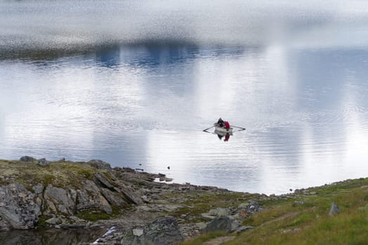 two unknown men in a rowing boat on a lake in norway