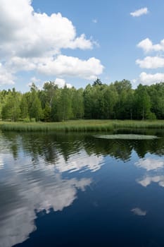Reservoir at the red moor in the high Rhoen, Hesse, Germany. With blue sky and white clouds and reflection in the water