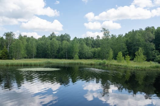 Reservoir at the red moor in the high Rhoen, Hesse, Germany. With blue sky and white clouds and reflection in the water
