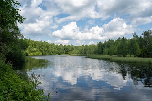 Reservoir at the red moor in the high Rhoen, Hesse, Germany. With blue sky and white clouds and reflection in the water