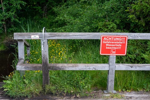 Sign reading "Attention! Danger zone! Note water depth"" and a sign next to a water tap reading ""No drinking water"" in green nature"
