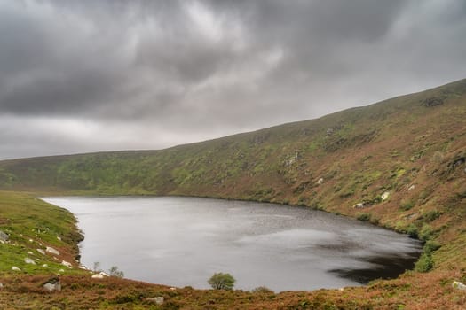 Lake, Lough Bray surrounded by mountains and covered in moody, dramatic storm clouds. Hiking in Wicklow Mountains, Ireland