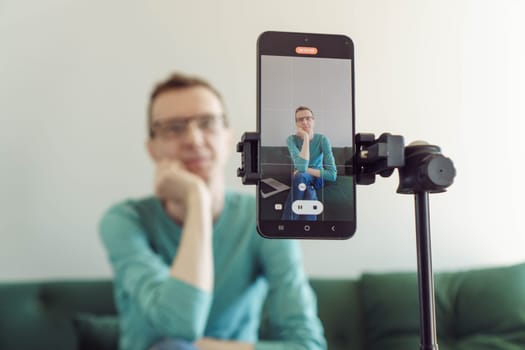 Blogging. In foreground is phone screen mounted on tripod with image from camera of male blogger recording his video. Modern technologies. Online training. Video recording of trainings.